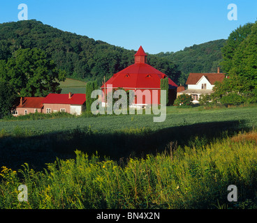 Pepin County, WI Farm with octagonal red barn under a forested hillside Stock Photo