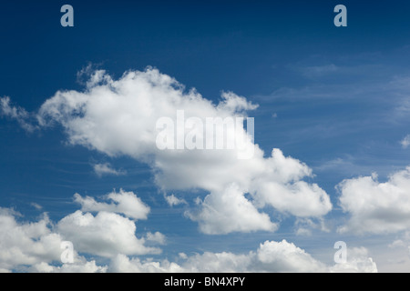 Weather small fluffy white cumulus clouds below cirrus in blue sky on summer’s day