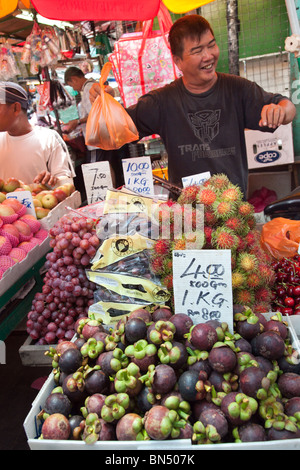 A street vendor sells mangosteens and other fruit in an Asian fruit market in Malaysia Stock Photo