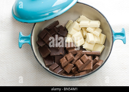 Dark, white, and milk chocolate chunks in pot to be melted for fondue Stock Photo