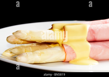 some asparagus enrolled with ham on a plate with black background Stock Photo