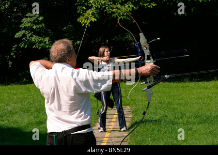 UK, England, Cheshire, Stockport, Cheadle, Bruntwood Park, male and female archers drawing bows in archery group Stock Photo