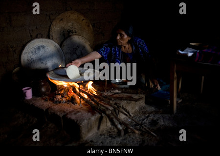 A Mayan Tzotzil woman makes corn tortillas for tourists in her souvenir shop in Zinacantan, Chiapas, Mexico. Stock Photo