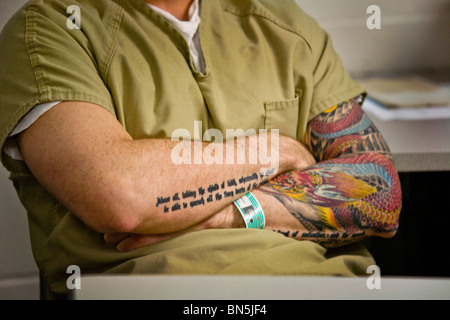 Tattoos contrast with prison clothing and prisoner identification wristband at the Santa Ana, CA, city jail. MODEL RELEASE Stock Photo