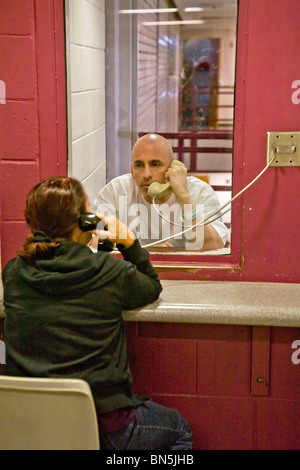 A prisoner talks with his wife using a telephone at the Santa Ana, CA, city jail. Note cell block in background. MODEL RELEASE Stock Photo