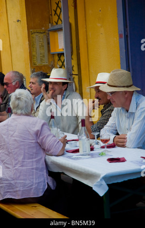 Arles, France - Group of French Men in Summer Hats, Sharing Drinks on Terrace of Old French Cafe Bar, Authentic French lifestyle Stock Photo