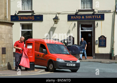 Postman emptying post-box in front of Hand & Shuttle pub, Padiham, Lancashire, England UK Stock Photo