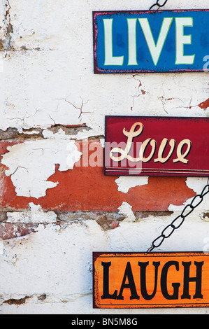 Live, Love, Laugh, old metal garden signs on a painted brick wall Stock Photo
