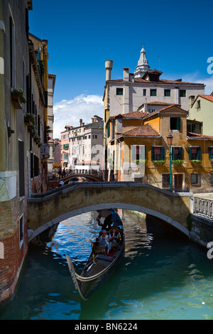A Gondola glides along a picture perfect canal in Venice, Golfo di Venezia, Italy Stock Photo