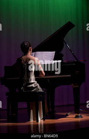 A young woman in evening dress plays a grand piano onboard the Kiso Ferry enroute to Hokkaido. Stock Photo