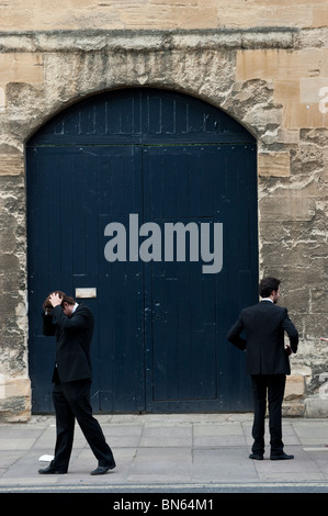 Two male students in evening dress - one holding his head in his hands - outside Wadham College, Oxford Stock Photo