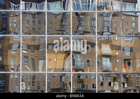 glass panels of a building in Canary Wharf, London, England, distorting the reflections of another building Stock Photo