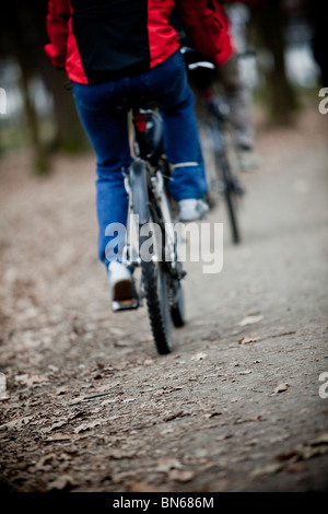 Two bicyclists going on a wood track - front focus Stock Photo