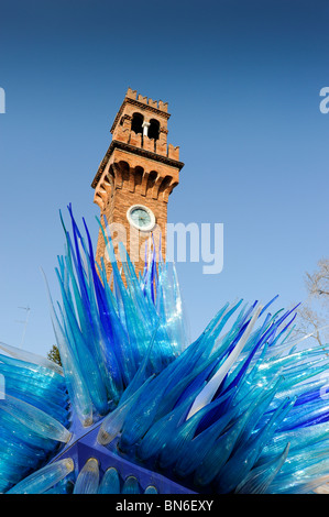 Striking blue glass sculpture with old clock tower in backround at Murano Venice Italy Stock Photo