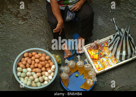 An early morning market seller in the village of Ubud, Bali, selling eggs, soup and other assorted items. Stock Photo