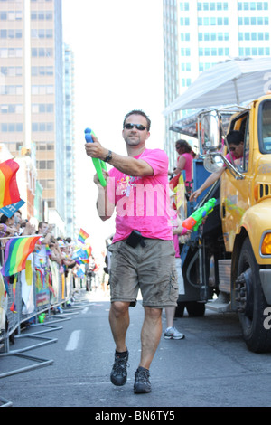 man in pink shirt shooting water gun on street Stock Photo