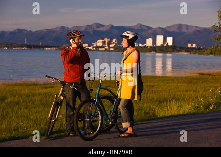 Bicyclists rest and take self-portraits along the Tony Knowles Coastal Trail with Anchorage in the background, Alaska Stock Photo
