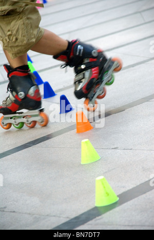 young guy skating slalom around colorfull cones Stock Photo
