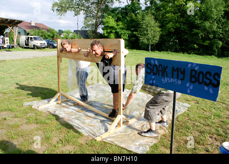 Throwing sponges at people in stocks as team building exercise Stock Photo