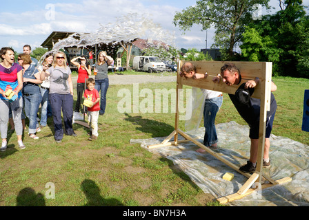 Throwing water at people in stocks as team building exercise Stock Photo