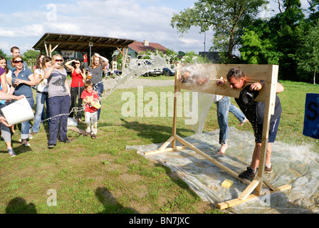 Throwing water at people in stocks as team building exercise Stock Photo