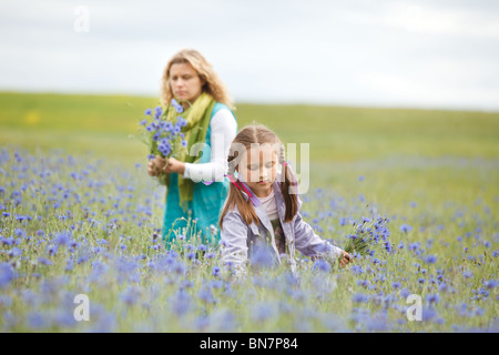 Mother and daughter picking blue flowers in a field Stock Photo