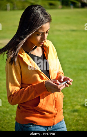 16 year years old Hispanic American girl texting using iPhone  mobile phone. MR  © Myrleen Pearson Stock Photo
