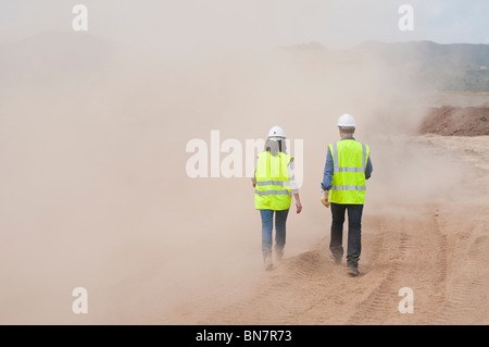Construction workers walking in cloud of dust Stock Photo