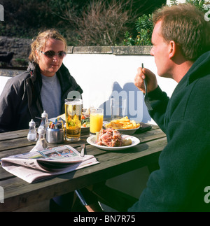 A couple drinking cider and eating lunch at an outside restaurant in Wales, UK Stock Photo