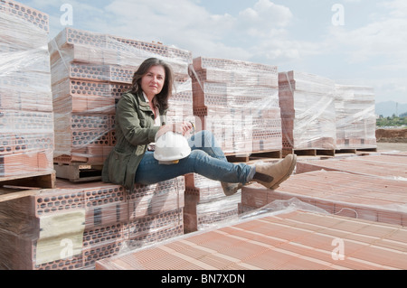 Caucasian construction worker sitting on stack of bricks Stock Photo