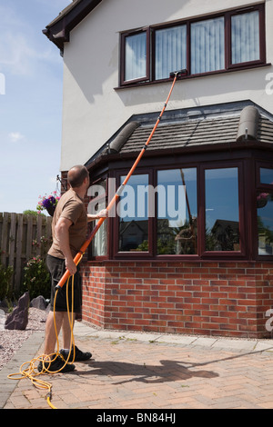 Window cleaner using a soapless pure water fed long pole and brush window cleaning system to reach high first floor windows Stock Photo