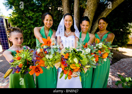 Mixed-race bride and her bridesmaids proudly display their flowers before a formal outdoor wedding in Orange, CA. MODEL RELEASE Stock Photo