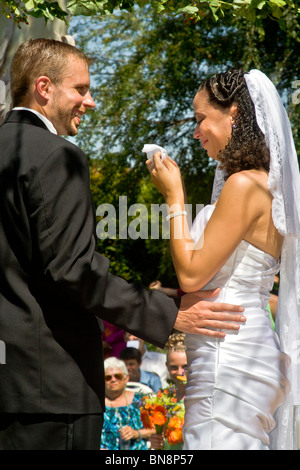 A mixed-race bride cries with happiness at her formal outdoor wedding ceremony in Orange, CA. Note bridegroom. Stock Photo