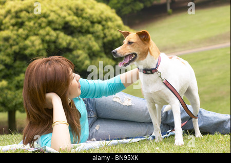 Woman lying down with her dog in a park Stock Photo