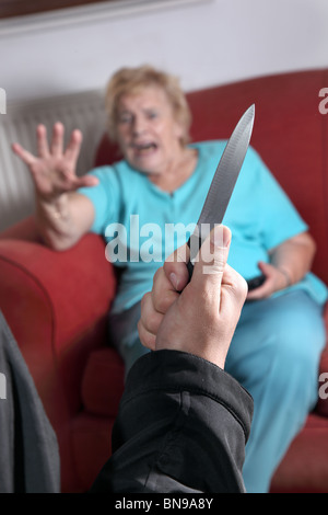 Knife pulled as terrified elderly woman looks towards the attacker Stock Photo