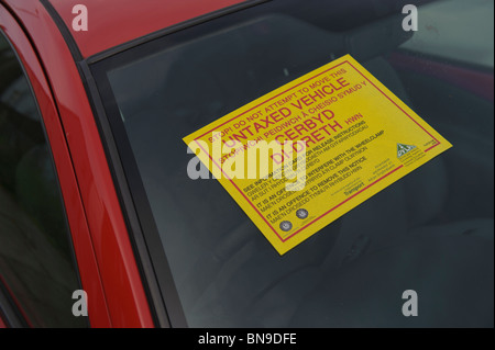 Warning sticker on the window of a car with no road tax clamped by the DVLA, UK Stock Photo