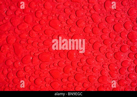 Close up macro photograph of rain drops on a red table Stock Photo