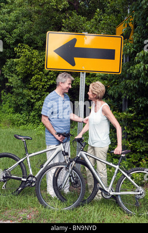 Senior man and woman meeting on bikes at a sign Stock Photo