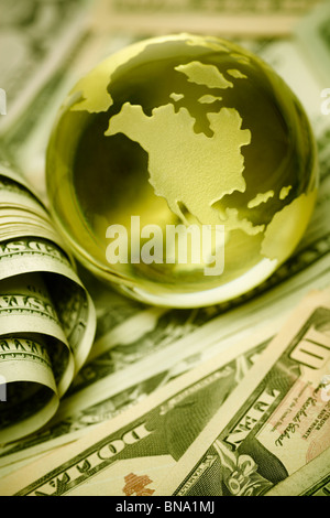 glass globe and US dollar bills in closeup, selective focus on nearest part
