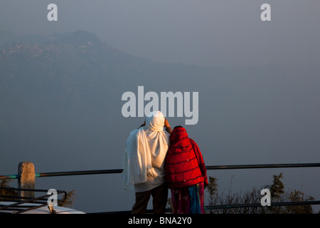 A couple watches the sunrise &  panoramic view of Kanchenjunga massif as seen from Tiger Hill in Darjeeling, West Bengal, India.
