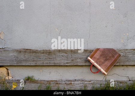 A handbag hangs abandoned on a old wall. Stock Photo