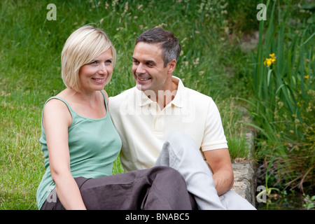 Young couple sitting by lake Stock Photo
