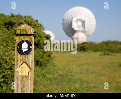 South West Coast path waymarker with massive  dishes of Morwenstow GCHQ radio satellite station in the background Stock Photo