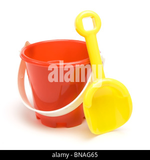 Kids red bucket and yellow spade summer holiday concept isolated against white background. Stock Photo