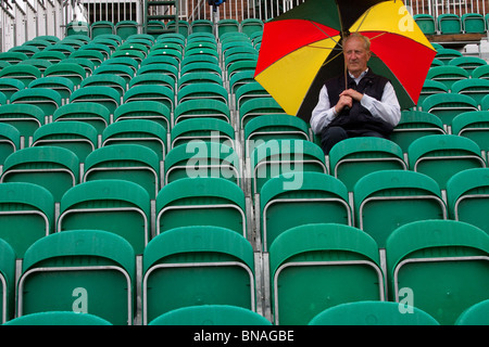 Rows of spectator seating, Man (MR) with large multi-coloured umbrella  at the139th British Open Golf 2010, July 15-18, St Andrews, Scotland Stock Photo