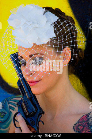Tattooed bride against graffiti background with hand gun Stock Photo