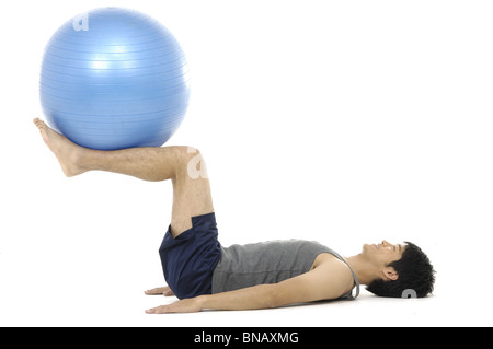Side profile of a young man exercising with a fitness ball Stock Photo