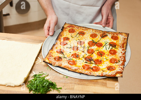 Male chef making pizza in commercial kitchen Stock Photo