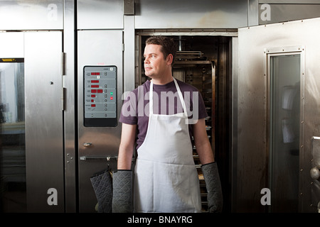 Male chef standing in front of oven Stock Photo