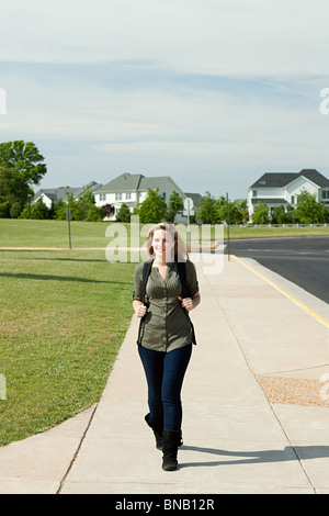 Female high school student walking along pavement Stock Photo